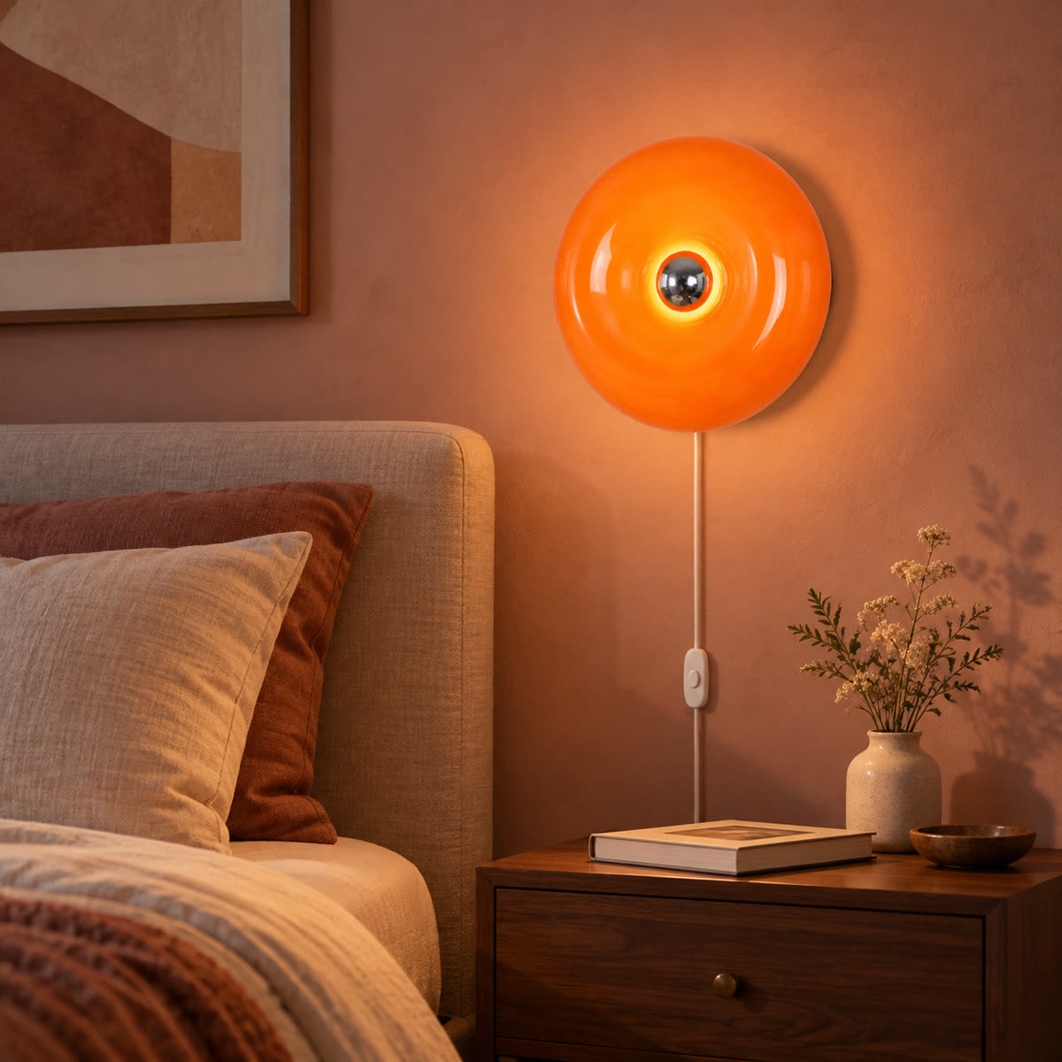 Lampada da parete con anello in vetro ambrato, montata sopra un comodino in camera da letto.